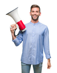 Young handsome man yelling through megaphone over isolated background with a happy face standing...