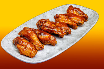 Plate of barbecued chicken wings on a yellow and red gradient background