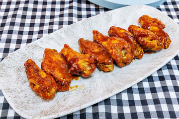 Plate of barbecued chicken wings on a black and white checkered tablecloth