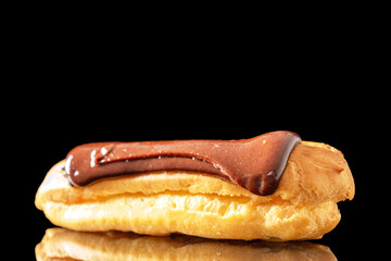 One delicious chocolate eclair, close-up isolated on black.