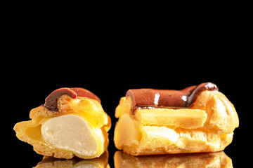 Two halves of a delicious chocolate eclair, close-up isolated on black.