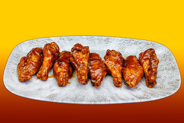 Plate of barbecued chicken wings on a yellow and red gradient background
