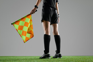 Legs of female referee in sportswear standing with flag, signaling for an offside on the near side...