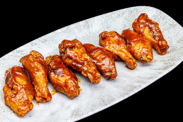 Plate of barbecue chicken wings on black background