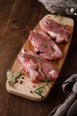 a piece of fresh raw pork meat with spices on a brown wooden table. Meat with spices