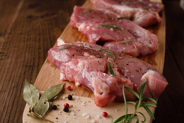 a piece of fresh raw pork meat with spices on a brown wooden table. Meat with spices