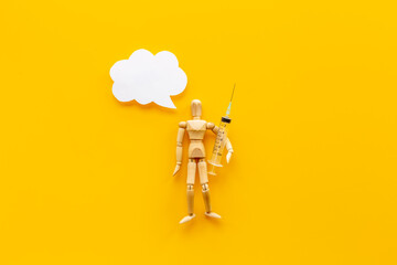 Wooden dummy man with syringe and vaccine. Medicine and healthcare concept