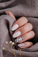 Woman's hand with a beautiful oval-shaped manicure. Autumn trend, beige color polishing with...