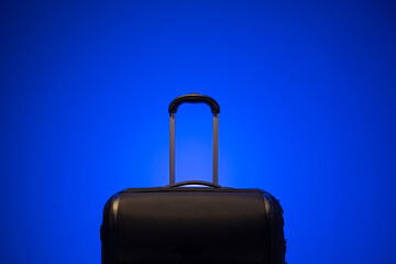Black travel luggage case with metal grab handle isolated again blue background. Close up studio shot, no people