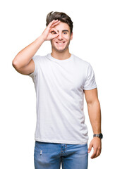 Young handsome man wearing white t-shirt over isolated background doing ok gesture with hand smiling, eye looking through fingers with happy face.