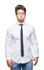 Young business man wearing glasses over isolated background puffing cheeks with funny face. Mouth inflated with air, crazy expression.