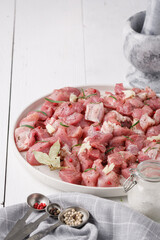 a piece of fresh raw pork meat with spices on a white wooden table. Meat with spices