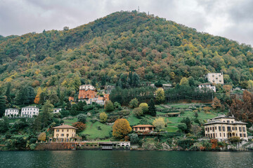 Fototapeta na wymiar Villa Cornaggia is surrounded by colorful mansions on the wooded shores of Lake Como. Italy