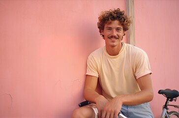 Retro 80s style handsome young man with mustache, leaning on a peach fuzz colored wall