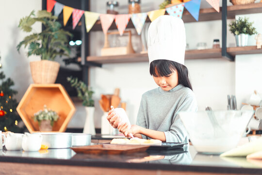 Little asian girl making cake and cooking food for Christmas cake and dinner party on holidays