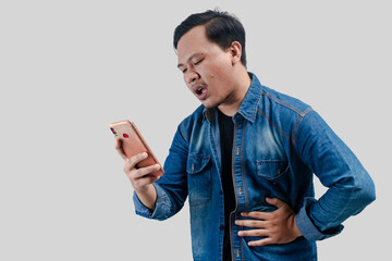 Young asian man having stomach ache or indigestion and pressing his stomach while looking his...