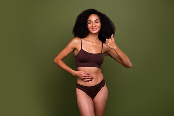 No retouch photo of attractive charming healthy woman wear brown lingerie touch stomach thumb up isolated on khaki color background