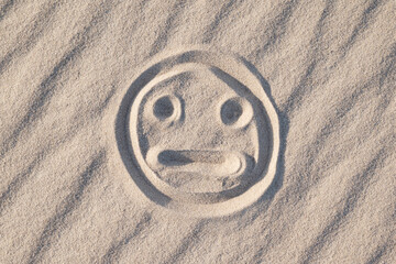 Sad and bewildered smile on sand. Negative emotions, strange feeling concept