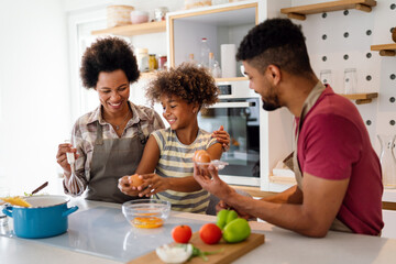 Overjoyed young african american family with kid have fun cooking at home together, - obrazy, fototapety, plakaty