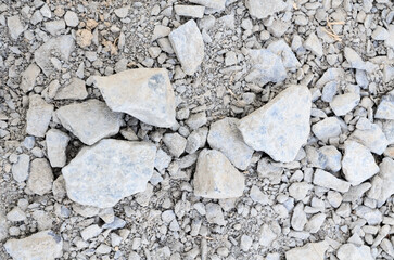Abstract background with crushed gravel and small little grey rocks and stones, close-up view from directly above