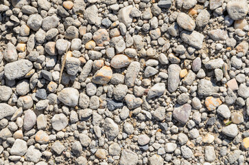 Abstract background with crushed gravel and small little grey rocks and stones, close-up view from directly above