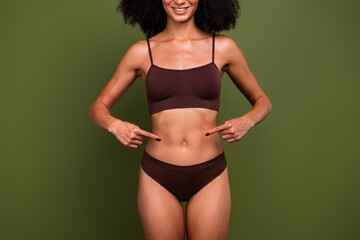 Cropped no retouch photo of charming slender girl showing her thin waist isolated on khaki color...