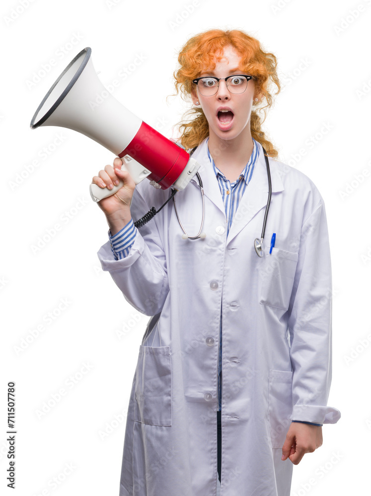 Sticker young redhead doctor woman holding megaphone scared in shock with a surprise face, afraid and excite