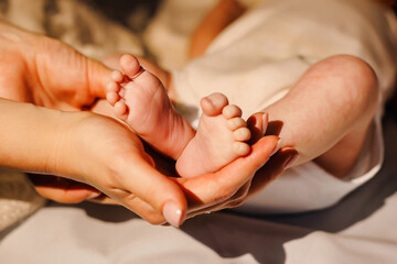 Close-up of mother's hands holding newborn baby feet