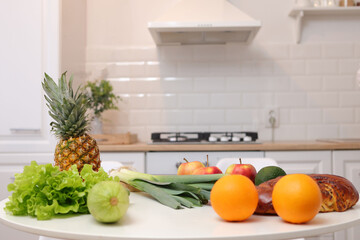 Beautiful kitchen interior design features white table adorned with group of fresh fruits and vegetables creating refreshing and healthy atmosphere with organic meals