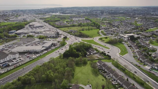 Aerial view on traffic in complicated road junction and Galway city in the background. Aerial view on road junction with dual road way and high density urban area with green zones.