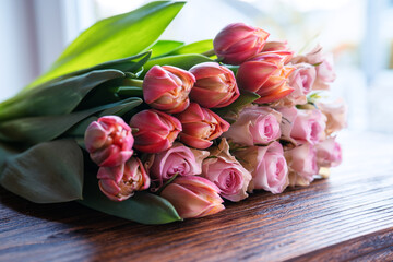 Bouquet of beautiful pink roses and tulips on dark wood. Concept background for mother's day,...