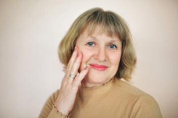 Smiling mature woman touching face in studio