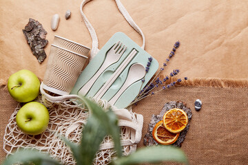 Eco-friendly, natural, plastic free, zero waste tableware with dry oranges, apple, lavender. Eco shopping bag on crumpled paper. Sustainable lifestyle.