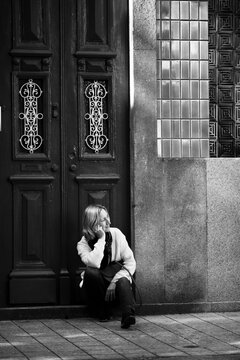 A woman sitting on the doorstep of a traditional Portuguese house. Black and white photo.