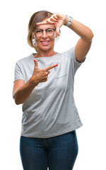 Middle age senior hispanic woman wearing glasses over isolated background smiling making frame with hands and fingers with happy face. Creativity and photography concept.