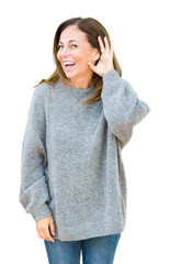 Beautiful middle age woman wearing winter sweater over isolated background smiling with hand over...