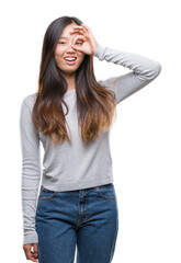 Young asian woman over isolated background doing ok gesture with hand smiling, eye looking through fingers with happy face.