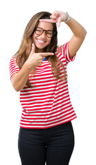 Obraz na płótnie Canvas Young beautiful brunette woman wearing glasses and stripes t-shirt over isolated background smiling making frame with hands and fingers with happy face. Creativity and photography concept.