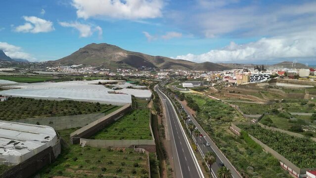 Flying over the Northern road in Gran Canaria, Canary Islands from vertical drone, palm trees, road and the imposing Amagro Mountain of G&aacute;ldar, Filmed in Height with a drone in 4k