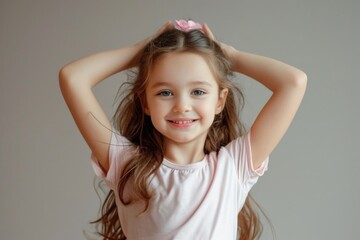A young girl holding her hair up in the air. This image can be used for hairstyling tutorials or showcasing different hair accessories