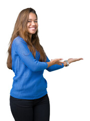 Young beautiful brunette woman wearing blue sweater over isolated background Inviting to enter...