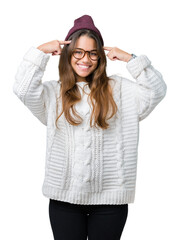 Obraz na płótnie Canvas Young beautiful brunette hipster woman wearing glasses and winter hat over isolated background Smiling pointing to head with both hands finger, great idea or thought, good memory
