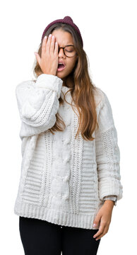 Young beautiful brunette hipster woman wearing glasses and winter hat over isolated background Yawning tired covering half face, eye and mouth with hand. Face hurts in pain.