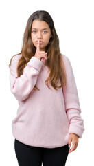 Young beautiful brunette woman wearing pink winter sweater over isolated background asking to be quiet with finger on lips. Silence and secret concept.