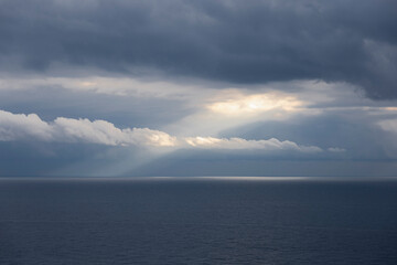 Clouds on the sea.
Light ray of the sun through the clouds on the blue sea. Liguria, Italy.