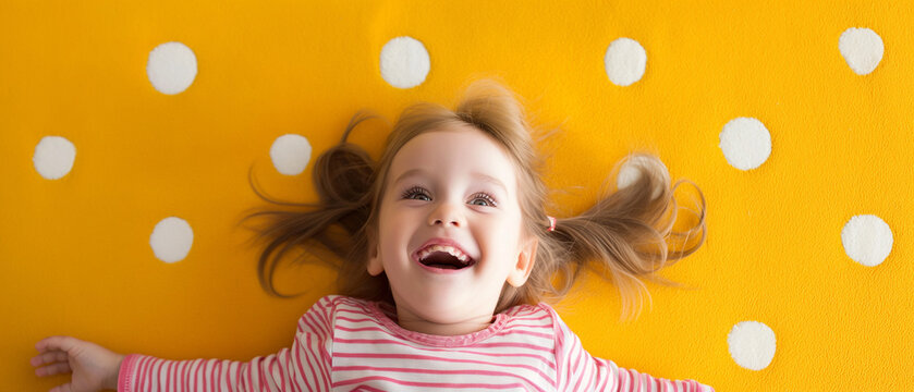 Criança feliz deitada em um tapete amarelo com bolinhas brancas