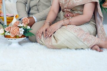 Obraz na płótnie Canvas Bride and groom sitting on the floor with flowers for thai wedding traditions, wedding concept.