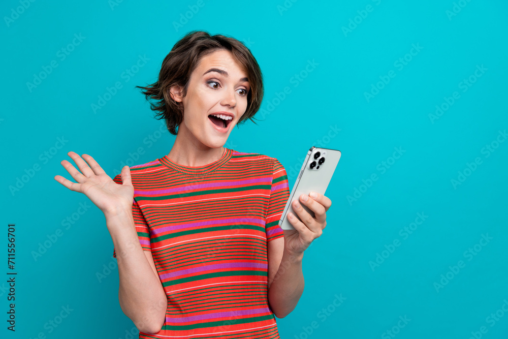 Sticker Photo of excited cheerful woman dressed striped t-shirt waving palm at smartphone on video call isolated on turquoise color background