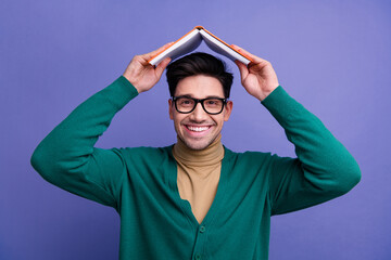 Photo of positive smart cheerful man wear trendy green clothes hold book above head isolated on...