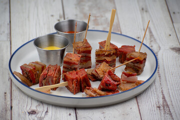Vegan seitan pork belly appetizer, white plate, wooden table